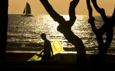 A tourist carries an inflatable raft while walking against the setting sun on Waikiki Beach in Honolulu, Hawaii, January 2, 2010. (Xinhua/Reuters Photo)