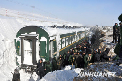 Armed police and railway workers clear the snow covered railway in Shangdu, north China's Inner Mongolia Autonomous Region, January 4, 2010. More than 1,400 passengers were evacuated. Xinhua