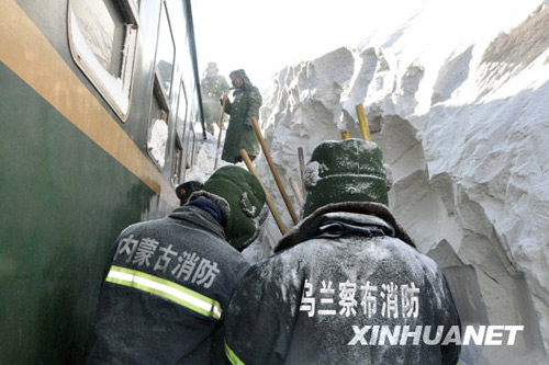 Armed police and railway workers clear the snow covered railway in Shangdu, north China's Inner Mongolia Autonomous Region, January 4, 2010. More than 1,400 passengers were evacuated. [Xinhua]