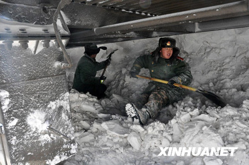 Armed police and railway workers clear the snow covered railway in Shangdu, north China's Inner Mongolia Autonomous Region, January 4, 2010. More than 1,400 passengers were evacuated. [Xinhua]