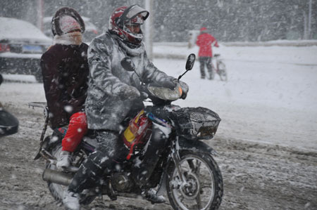 A motorcyclist goes slowly on the slippery road in snow in downtown Rushan, east China's Shandong province, Jan. 4, 2010. [Photo: Xinhua]