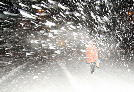 A resident struggles his way on the slippery road in snow in downtown Yantai, east China's Shandong province, Jan. 4, 2010. The traffic in this costal city became seriously difficult as a snowstorm raided it on Monday. [Photo: Xinhua