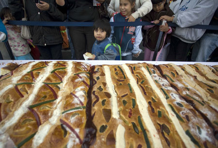 A child looks at the traditional &apos;Rosca de Reyes&apos; in Mexico City, capital of Mexico, on Jan. 3, 2010. The biggest &apos;Rosca de Reyes&apos; of the world, of 720 meters length and 12,000 kg weight, was distributed to 250,000 people at the Zocalo square in Mexico City. [Xinhua]