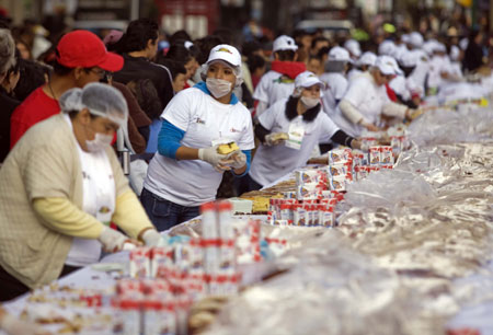 People cut the traditional &apos;Rosca de Reyes&apos; baked for Epiphany in Mexico City, capital of Mexico, on Jan. 3, 2010. The biggest &apos;Rosca de Reyes&apos; of the world, of 720 meters length and 12,000 kg weight, was distributed to 250,000 people at the Zocalo square in Mexico City. [Xinhua] 