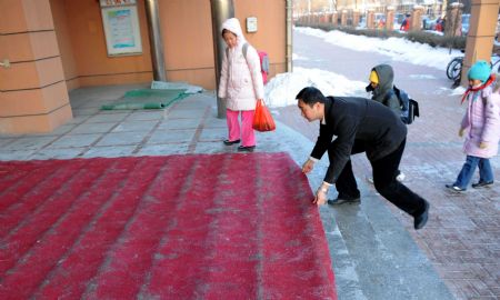 A teacher lays a skidproof carpet in front of a building in Tianjin, north China, on Jan. 5, 2010. Primary and middle schools in the city resumed classes Tuesday after a one-day break due to the heavy snowfall. (Xinhua/Liu Haifeng)