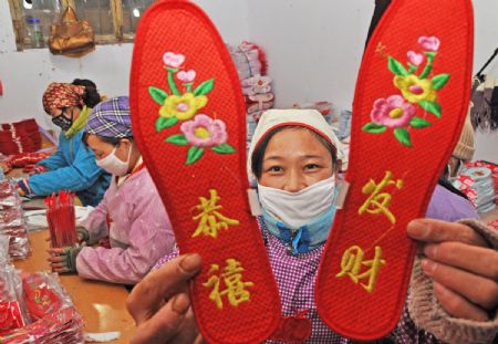 A woman shows a pair of handmade shoe-pads in Yiyuan County of east China's Shandong Province, Jan. 5, 2010. Red shoe-pads, meaning best wishes and good luck, are welcomed as the Chinese lunar new year approaches.(Xinhua/Zhao Dongshan)