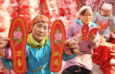 A woman shows a pair of handmade shoe-pads in Yiyuan County of east China's Shandong Province, Jan. 5, 2010. Red shoe-pads, meaning best wishes and good luck, are welcomed as the Chinese lunar new year approaches.(Xinhua/Zhao Dongshan)