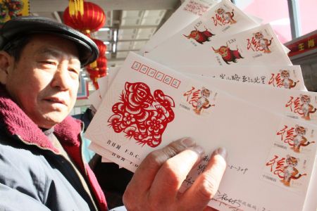 A man shows the first-day postal cover of the special stamp Tiger in Tianjin, north China, Jan. 5, 2010. 