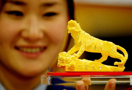 A customer looking at a gold tiger on display at a shopping mall in Shenyang, Liaoning province. Bullion gained more than 50 percent last year from $801 an ounce in January to US$1,226 an ounce in December. [Photo: China Daily]