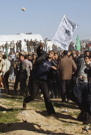 A Palestinian throws a stone at Egyptian soldiers during a gunbattle on the border between Egypt and the Gaza Strip January 6, 2010.