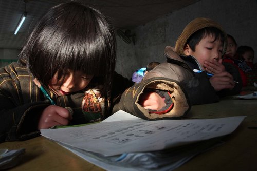 Students sit for an end-of-semester examination in the freezing classroom at the Fenghua Hope School in Haidian district yesterday. Nearly 500 students took their exams earlier than in previous years due to the lack of fuel to heat the school. [Photo/CFP]