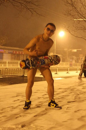 A young boy wearing shorts poses for photograph in the snow late at night on Ping&apos;an avenue, Beijing. [peopledaily.com.cn]