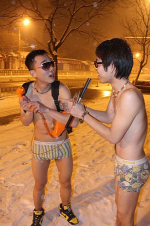 Two young boys wearing shorts pose for photograph in the snow late at night on Ping&apos;an avenue, Beijing. They acted as doing interviews.[peopledaily.com.cn]