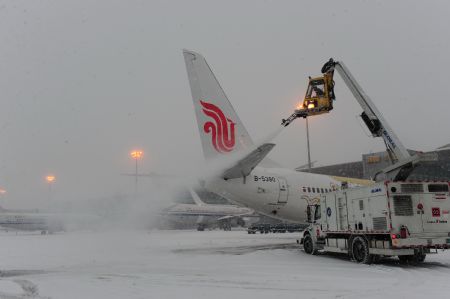 An ice-sweeping vehicle cleans a plane at the Capital International Airport in Beijing, capital of China, Jan. 3, 2010. Some departure flights were delayed and some were canceled due to the heavy snowfall in Beijing on Sunday. [Xinhua]