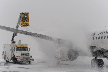 An ice-sweeping vehicle cleans a plane at the Capital International Airport in Beijing, capital of China, Jan. 3, 2010. Some departure flights were delayed and some were canceled due to the heavy snowfall in Beijing on Sunday. [Xinhua]