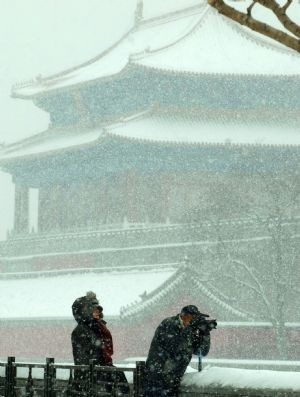 A man takes pictures of the snow-covered Forbidden City in Beijing, China, Jan. 3, 2010. Heavy snow hit Beijing on Sunday to close expressways, delay flights and disrupt bus services. [Xinhua]