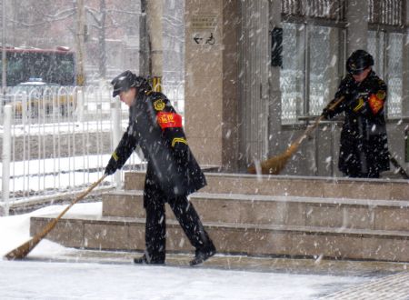 Staff members of Beijing subway clear the snow from the entrance of a subway station in Beijing, China, Jan. 3, 2010. Heavy snow hit Beijing on Sunday to close expressways, delay flights and disrupt bus services. [Xinhua]