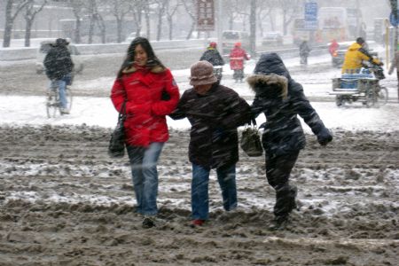 Pedestrians walk across a road in snow in Beijing, China, Jan. 3, 2010. Heavy snow hit Beijing on Sunday to close expressways, delay flights and disrupt bus services. [Xinhua]