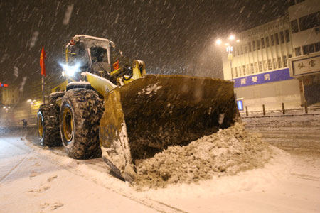 A bulldozer clears ice and snow in the early morning in downtown Yantai, east China&apos;s Shandong province, Jan. 4, 2010. The traffic in this costal city became seriously difficult as a snowstorm raided it on Monday.[Xinhua]