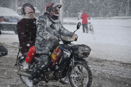 A motorcyclist goes slowly on the slippery road in snow in downtown Rushan, east China&apos;s Shandong province, Jan. 4, 2010. [Xinhua]