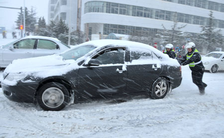 Traffic policemen push a car on the slippery road in snow in downtown Rushan, east China&apos;s Shandong province, Jan. 4, 2010. [Xinhua]