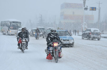 Vehicles run on the slippery road in snow in downtown Rushan, east China&apos;s Shandong province, Jan. 4, 2010. [Xinhua] 