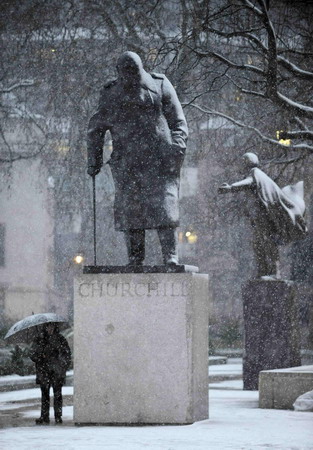 A man shelters from the snow next to the Chuchill statue in Parliament square, London January 6, 2010.[Chinadaily.com.cn via agencies] 