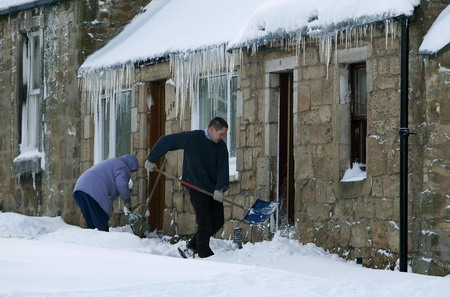 A man clears away snow from the front of his home in Pathhead in Midlothian, Scotland, January 6, 2010.[Chinadaily.com.cn via agencies] 