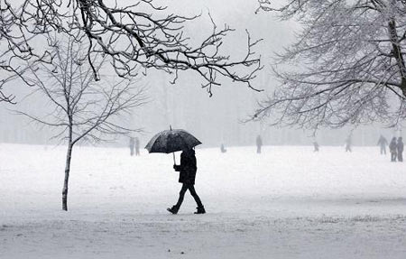 A man walks through the snow in Queen&apos;s Park in northwest London, January 6, 2010. Blizzards swept across central and southern England on Wednesday, bringing more road and rail chaos, forcing airlines to suspend flights and hundreds of schools to close. [Xinhua/Reuters]