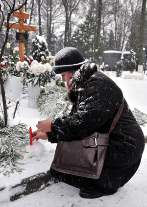 A woman lights a red candle in front of Russian ballerina Galina Ulanova's tomb marking Ulanova's 100th birth anniversary, in Moscow, Russia, Jan. 8, 2010. (Xinhua/Gao Fan)