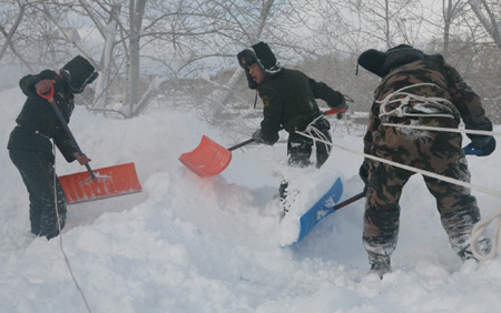 A contingent of Chinese People's Armed Police frontier defence detachment clear the snow on the vegetable greenhouse shed in Altay, northwest China's Xinjiang Uygur Autonoumous Rrgion, Jan. 7, 2010.