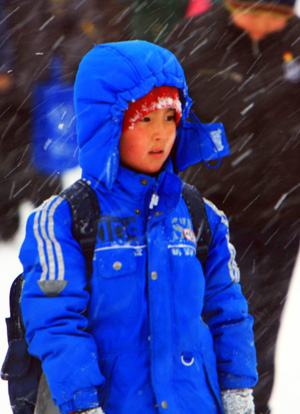 A boy wrapping himself up goes to school in the snow in Habahe County in Aletai, northwest China&apos;s Xinjiang Uygur Autonomous Region, Jan. 6, 2010.[Xinhua]