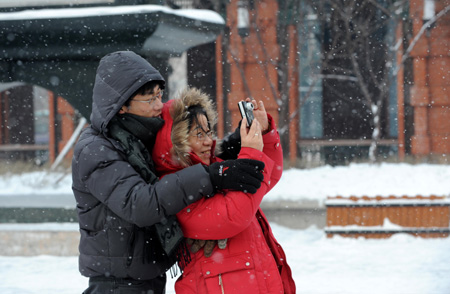 Tourists take pictures of snow-covered landscape at a square in the downtown of Harbin, northeast China&apos;s Heilongjiang Province, Jan. 7, 2010.[Xinhua]