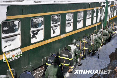 Armed police and railway workers clear the snow covered railway in Shangdu, north China&apos;s Inner Mongolia Autonomous Region, January 4, 2010. Due to heavy snowfall on Sunday, several trains were delayed and some were stranded in remote areas in Inner Mongolia, January 4, 2010. More than 1,400 stranded passengers were settled in the safe neighborhood in Shangdu by 14:00 Monday. [Xinhua]