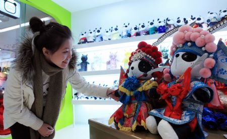 A girl is attracted by the cute Panda dolls with Peking Opera&apos;s makeup style, a novel doll brand series of Panda Town wrought by a group of young designers born after 1980s who returned to China after having finished education overseas, which makes its debut at a doll shop in Beijing, Jan. 10, 2010. [Luo Wei/Xinhua]