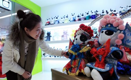 A girl is attracted by the cute Panda dolls with Peking Opera's makeup style, a novel doll brand series of Panda Town wrought by a group of young designers born after 1980s who returned to China after having finished education overseas, which makes its debut at a doll shop in Beijing, January 10, 2010. [Xinhua photo]