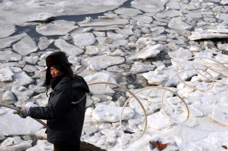 A mariculturist breaks the ice on the sea in Jiaozhou, east China's Shandong Province, Jan. 10, 2010.(Xinhua/Li Ziheng)