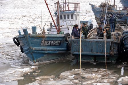 Police help move the vessels stucked by ice in Qingdao, east China's Shandong Province, Jan. 10, 2010.(Xinhua/Li Ziheng)