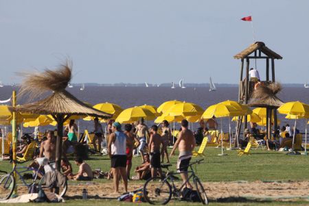 People enjoy the sunshine along the beach of La Plata river in Buenos Aires, the capital of Argentina, Jan. 9, 2010. [Marcelo Espinosa/Xinhua]