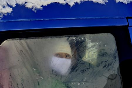A Kazak woman looks through a frosted window of the vehicle in Keketuohai Town of northwest China's Xinjiang Uygur Autonomous Region, Jan. 10, 2010.