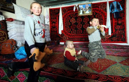 Kazak children enjoy the fruits in their warm house in Keketuohai Town of northwest China's Xinjiang Uygur Autonomous Region, Jan. 10, 2010.