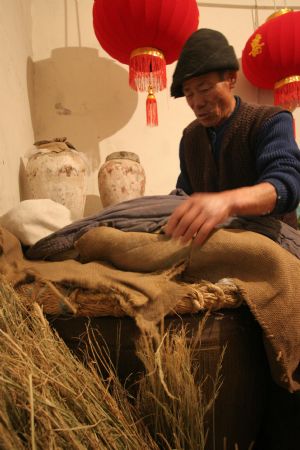 Ni Zhongyou wraps the wine jar for the sticky rice inside to ferment to make yellow rice wine in Kebei Village in Qixian Township of Shaoxing County, east China's Zhejiang Province, Jan. 10, 2010. 