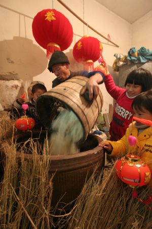  Ni Zhongyou (L2) pours sticky rice into a wine jar to make yellow rice wine in Kebei Village in Qixian Township of Shaoxing County, east China's Zhejiang Province, Jan. 10, 2010.