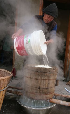 Ni Zhongyou cools sticky rice to make yellow rice wine in Kebei Village in Qixian Township of Shaoxing County, east China's Zhejiang Province, Jan. 10, 2010. 