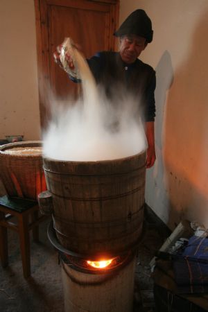 Ni Zhongyou pours sticky rice into a steamer to make yellow rice wine in Kebei Village in Qixian Township of Shaoxing County, east China's Zhejiang Province, Jan. 10, 2010.