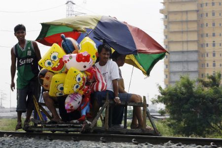 A wooden makeshift train with passengers moves along a railway line in Manila January 12, 2010. The makeshift train which does not run on fuel, is one of the cheapest form of transportations in the capital as local petroleum prices continue to rise in step with world market prices. [Xinhua/Reuters]