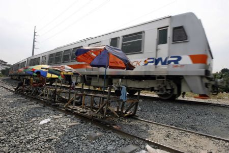 A Philippine National Railways train moves past a wooden makeshift train parked to receive passengers along a railway line in Manila January 12, 2010. The makeshift train which does not run on fuel, is one of the cheapest form of transportations in the capital as local petroleum prices continue to rise in step with world market prices. [Xinhua/Reuters]