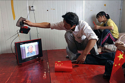 A migrant worker from Hefei, Anhui province, adjusts the TV set to improve the picture for the military parade broadcast during the celebration of the 60th anniversary of the People's Republic of China on October 1, 2009. 