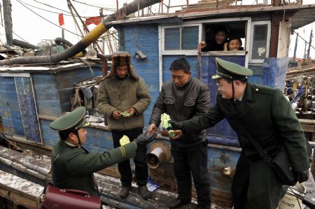 Policemen offer medicines to trapped fishermen in Laizhou, east China's Shandong Province, Jan. 12, 2010. The most severe icing situation in the past 30 years in the coast off Shandong Province continued to worsen amid cold snaps. Sea ice appeared last week along the coastline of the Bohai Sea and northern Yellow Sea as cold fronts pushed the temperature down to minus 10 degrees Celsius.
