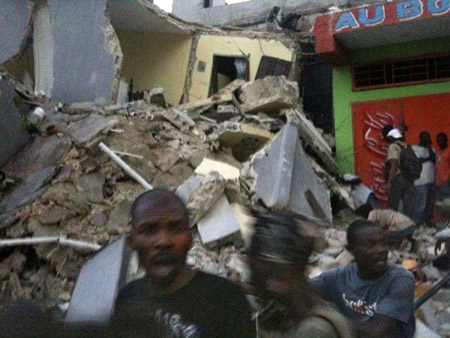 Scared people stand nearby a collapsed building after the 7.0 magnitude earthquake in Port-Au-Prince of Haiti, Tuesday, Jan. 12, 2010.